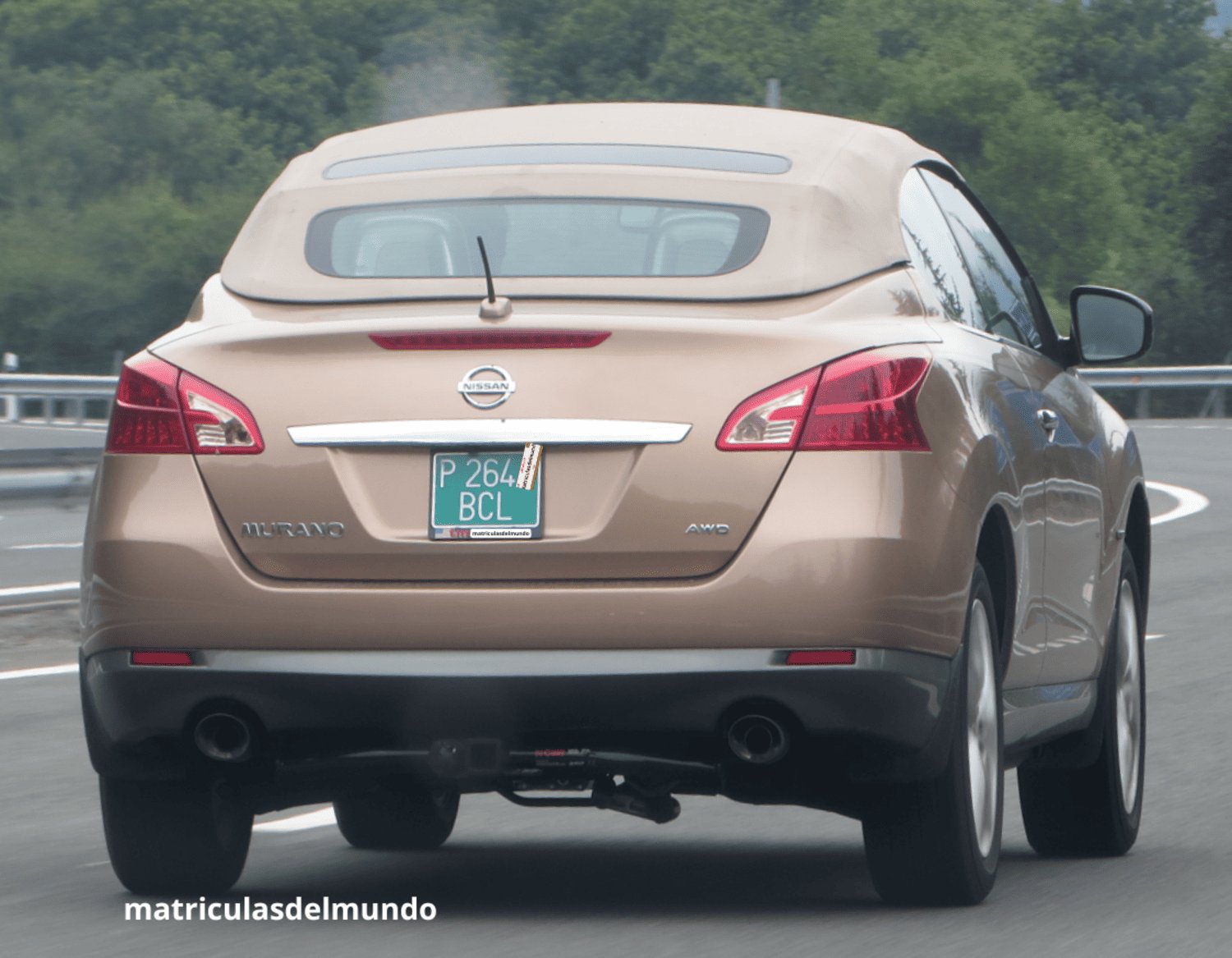 Coche SUV dorado Nissan Murano descapotable circulando por una autopista con matrícula verde provisional de España en un día nublado