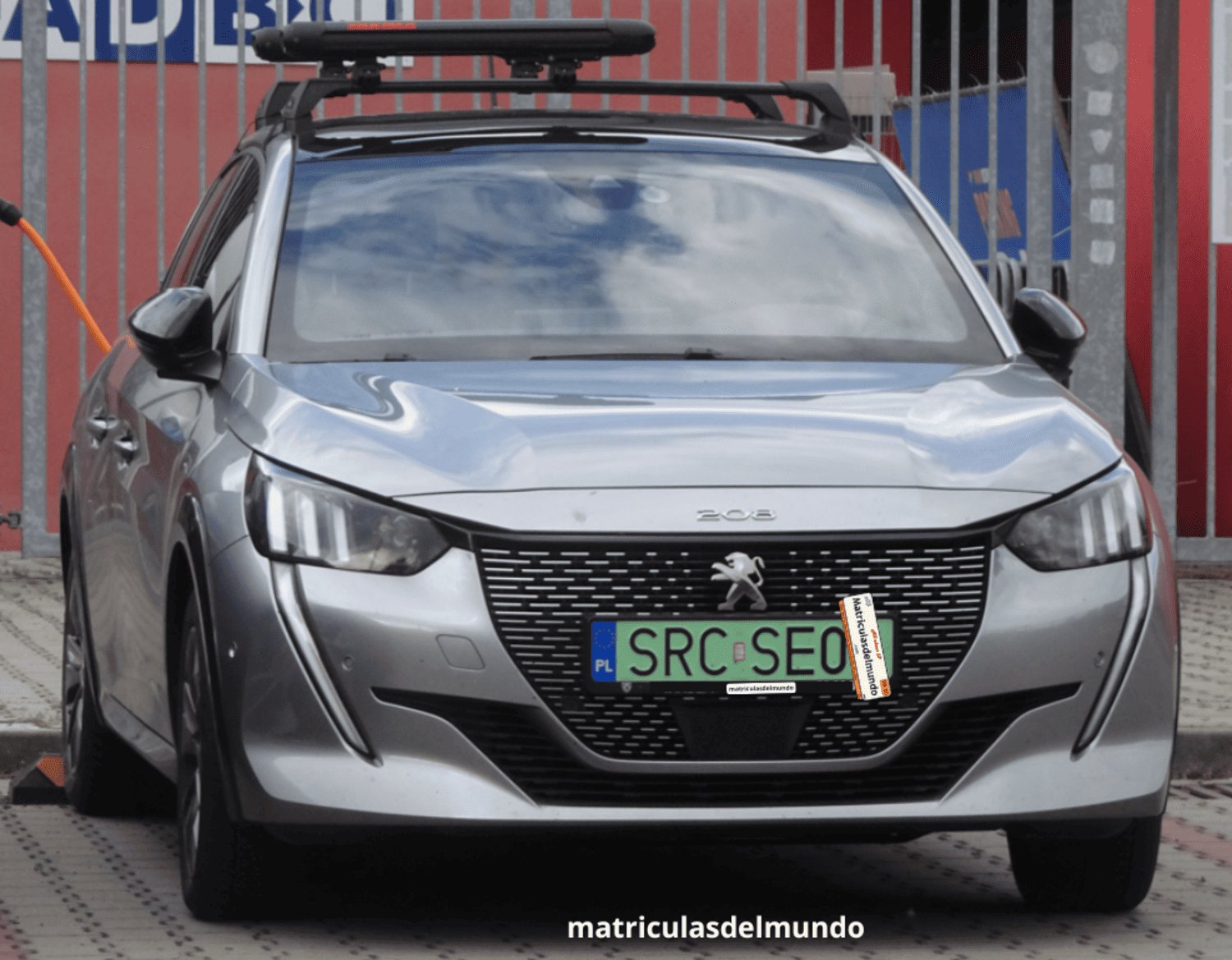 Pequeño coche Peugeot 208 gris con baca en el techo y matrícula verde que identifica a un vehículo eléctrico de la región de Racibórz con código SRC