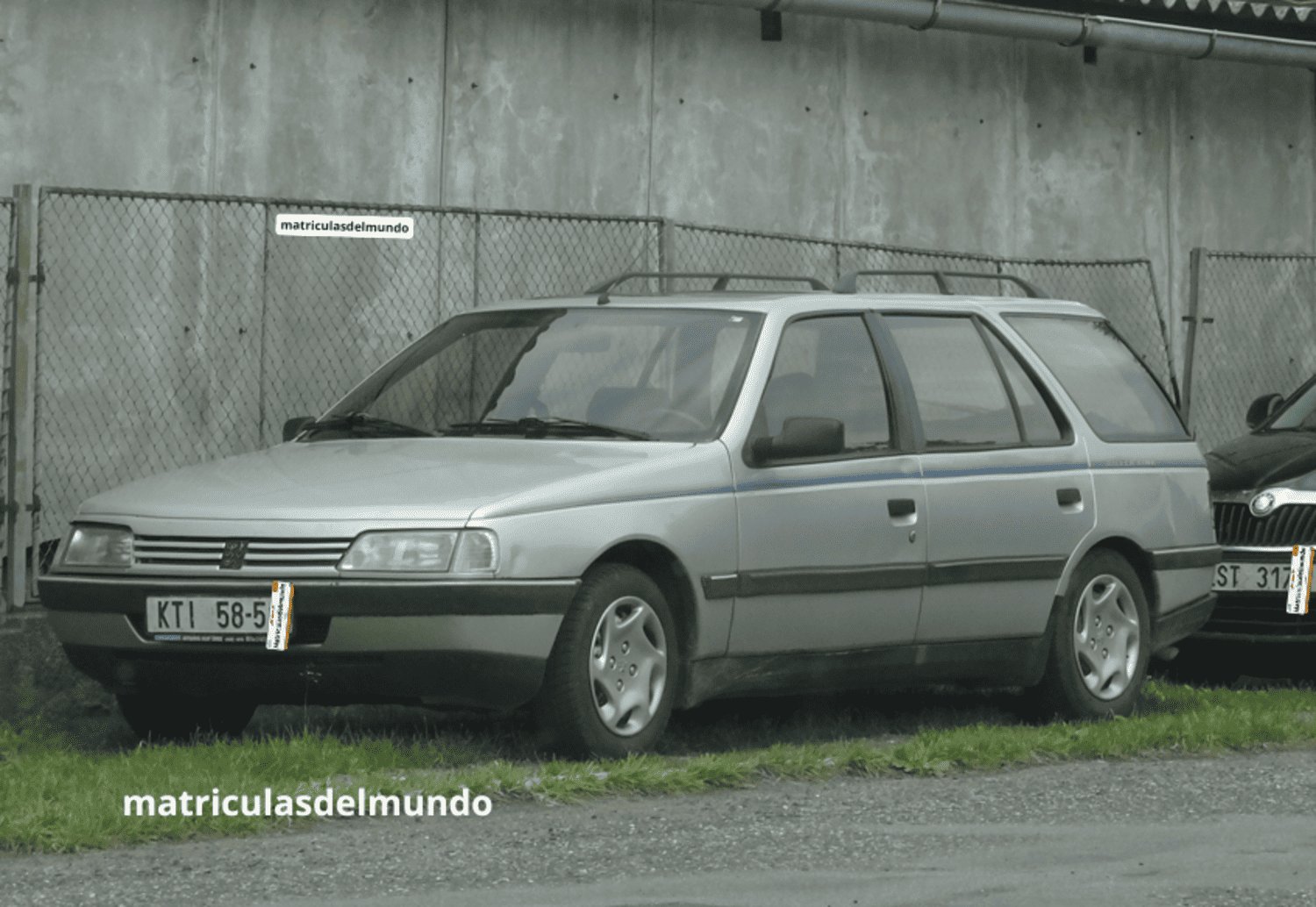 Peugeot 405 combi familiar color gris y antigua placa de matrícula provincial de República Checa para Klatovy aparcado junto a una valla en un prado