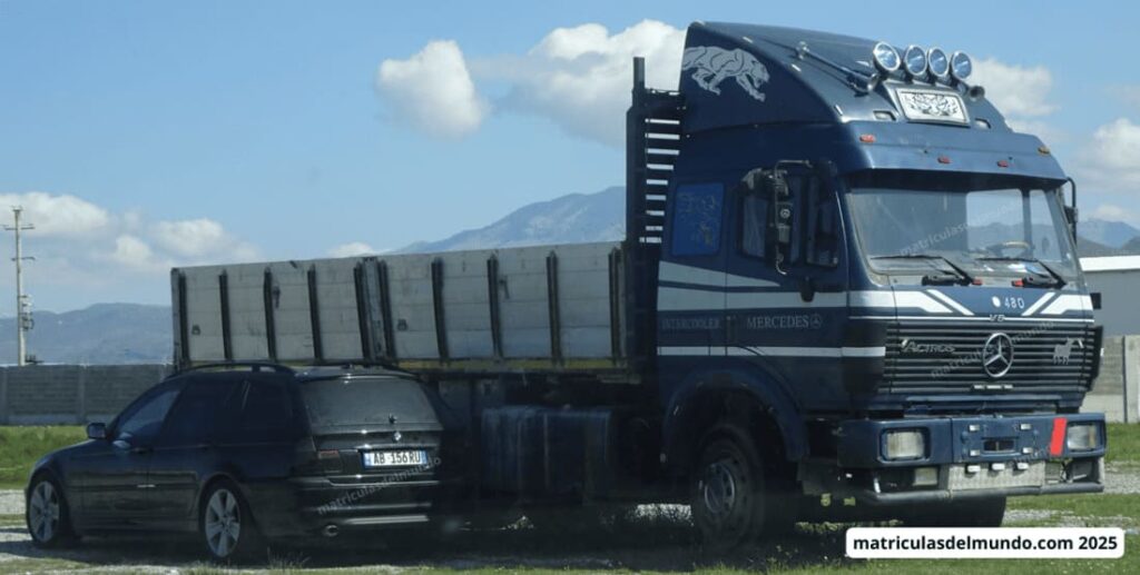 Camión Mercedes-Benz Actros azul decorado con pantera y matrícula de Albania junto a un BMW negro