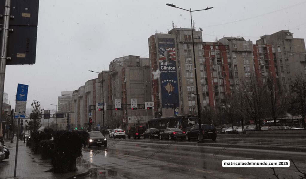 Mural de Bill Clinton en Pristina, Kosovo, con tráfico urbano – matrículas de coches en los Balcanes