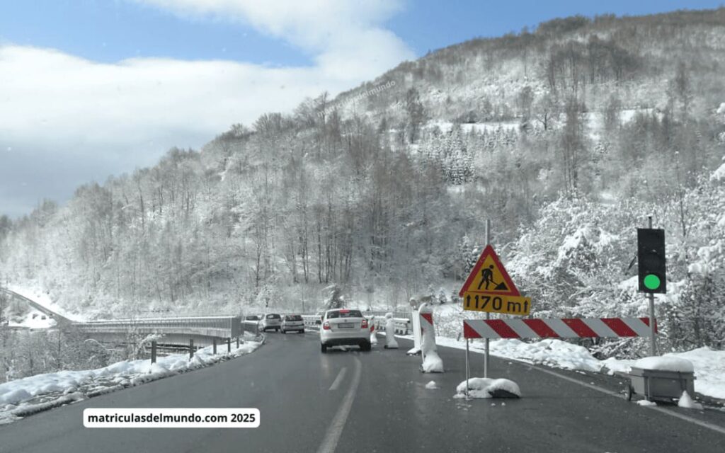 Carretera nevada en el Sandžak serbio con señal de obras – matrículas de coches en los Balcanes