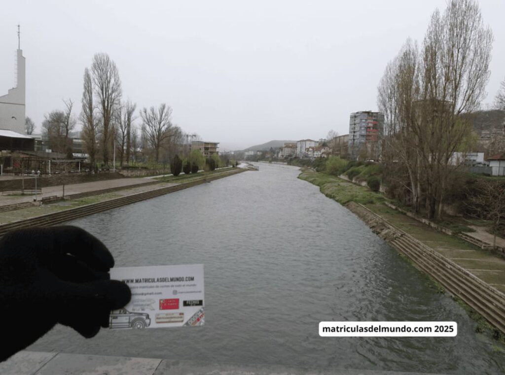 Vista del río Ibar desde un puente en Mitrovica, Kosovo, con una tarjeta de matriculasdelmundo.com en primer plano.