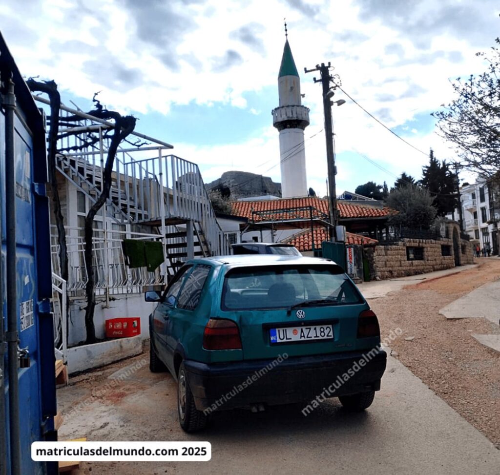 Volkswagen Golf verde con matrícula de Montenegro estacionado frente a una mezquita con minarete.